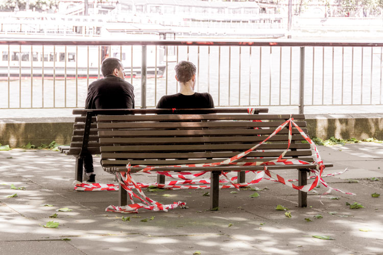 Two people sitting on half taped off street furniture