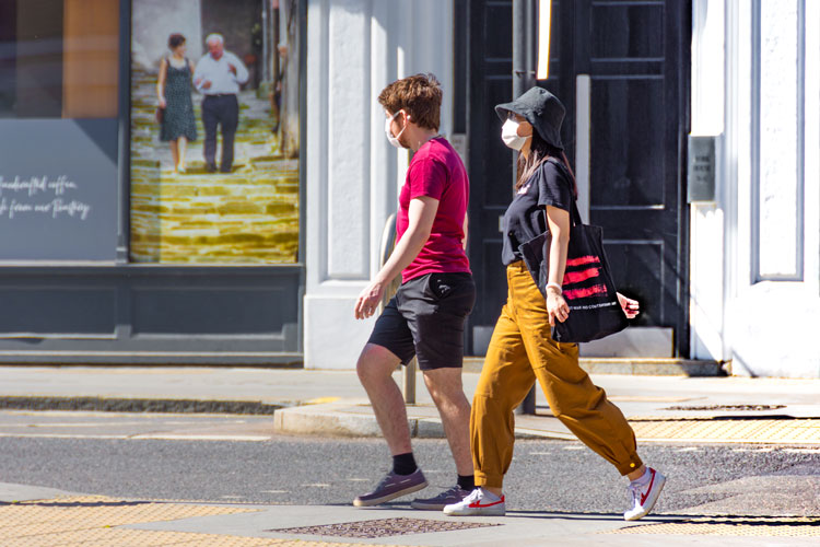 Two people with face masks walking in the city street