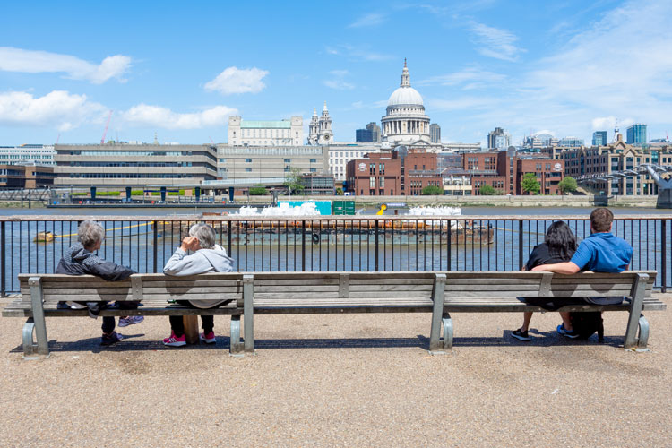 Observing social distancing on street bench with view of St Paul's in distance